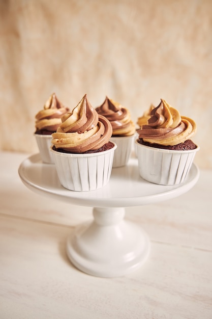 Vertical shallow focus closeup shot of delicious peanut butter cupcakes with creamy icing on a plate