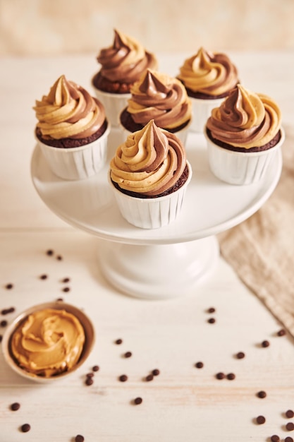 Free photo vertical shallow focus closeup shot of delicious peanut butter cupcakes with creamy icing in a plate