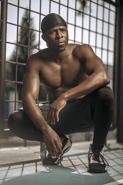 Vertical shallow focus shot of black basketball player relaxing after training in an outdoor court