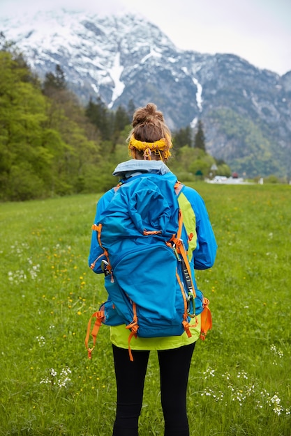 Foto gratuita colpo verticale di donna che viaggia attiva esplora la bellezza della natura, si erge contro il paesaggio di montagna