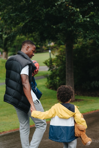 Vertical shot of an African-American child and his father in the park