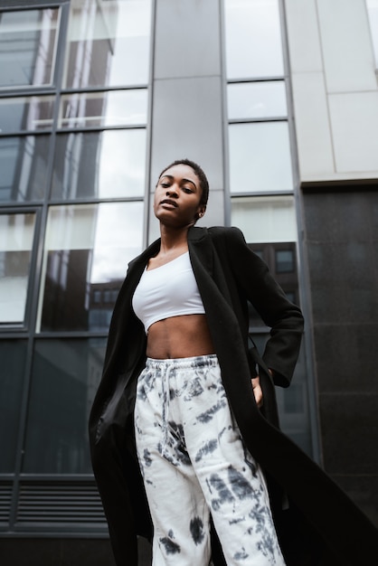 Free photo vertical shot of an african-american woman wearing a coat an posing in the street