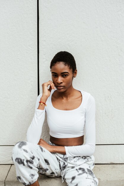 Vertical shot of an African-American woman wearing a white top and posing