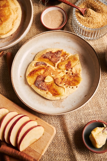 Foto gratuita colpo verticale di una frittella di mele con mele e altri ingredienti su un tavolo