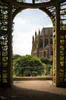 Free photo vertical shot of the arundel castle and cathedral from a beautiful arch covered in green foliage