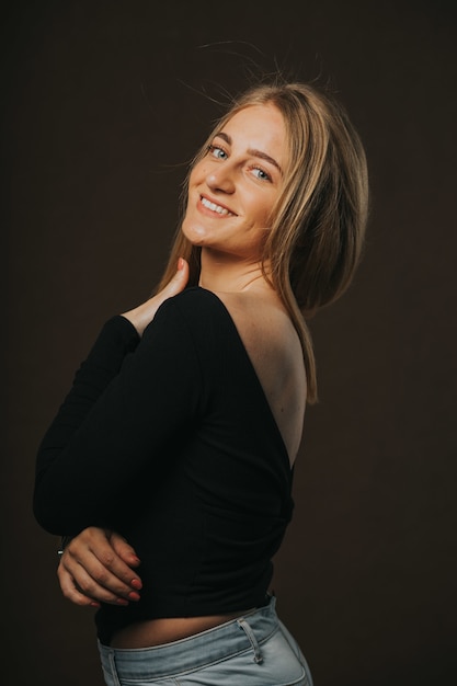 Vertical shot of an attractive blonde female posing while sitting on a barstool