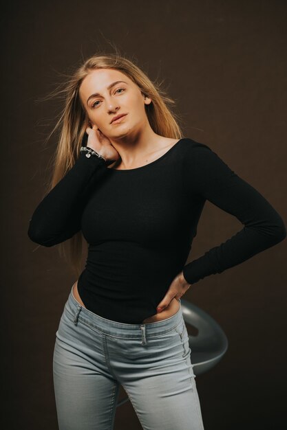 Vertical shot of an attractive blonde female posing while sitting on a barstool