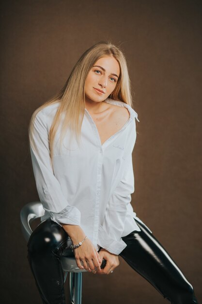 Vertical shot of an attractive blonde female posing while sitting on a barstool