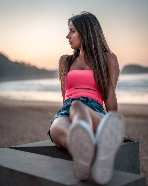 Vertical shot of an attractive female sitting on the beach by the ocean captured in Zarautz Spain