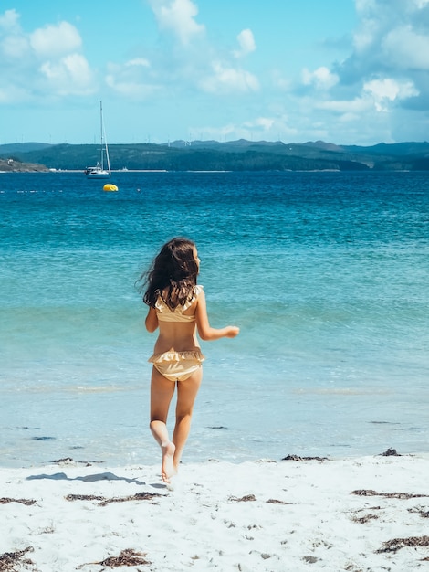 Vertical shot of the back of a little girl unrecognizable in a bikini