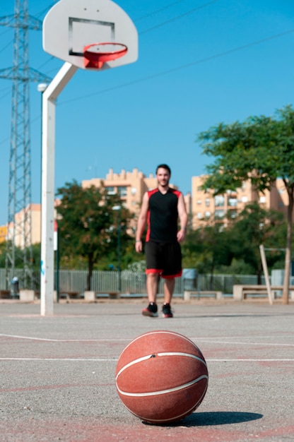 Vertical shot of a ball on a basketball court with a man playing