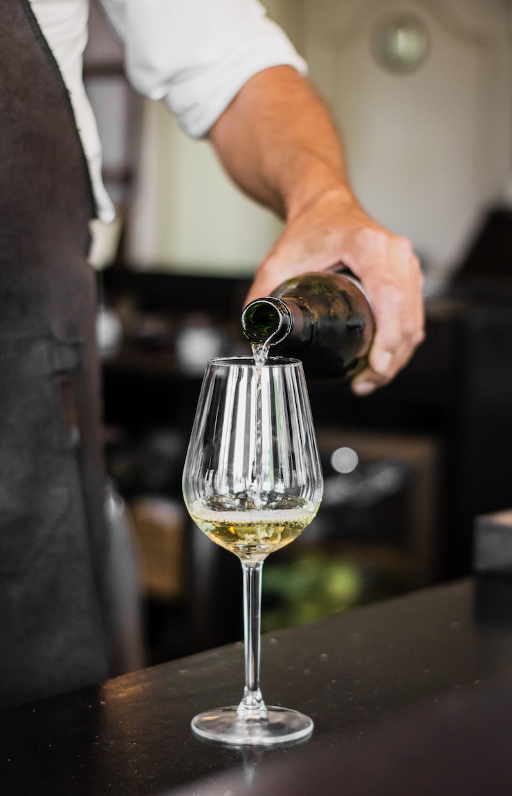 Free Photo vertical shot of a bartender pouring a wine into a glass