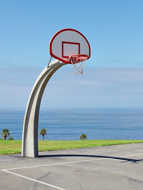 Vertical shot of a basketball hoop near the sea under the beautiful blue sky