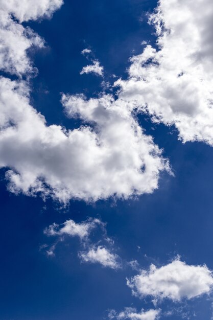 Vertical shot of the beautiful blue sky with breathtaking large white clouds