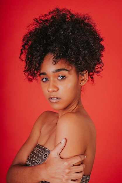 Free photo vertical shot of a beautiful hispanic female posing by a red background