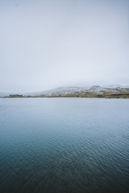 Free photo vertical shot of a beautiful lake surrounded by high mountains in finse, norway