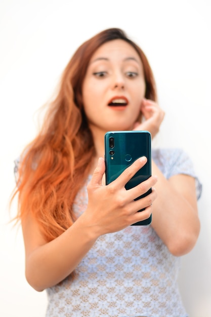 Vertical shot of a beautiful redhead lady looking at her phone shook