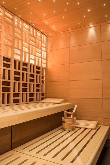 Vertical shot of a beautiful sauna room design with wall tiles and wooden bench