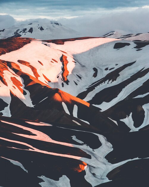 Вертикальная съемка красивых снежных холмов в сельской местности Исландии на заходе солнца