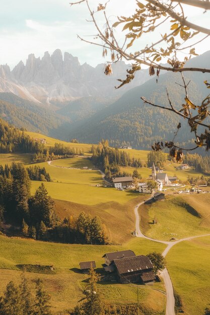 Вертикальный снимок красивой деревни на холме в окружении гор при дневном свете