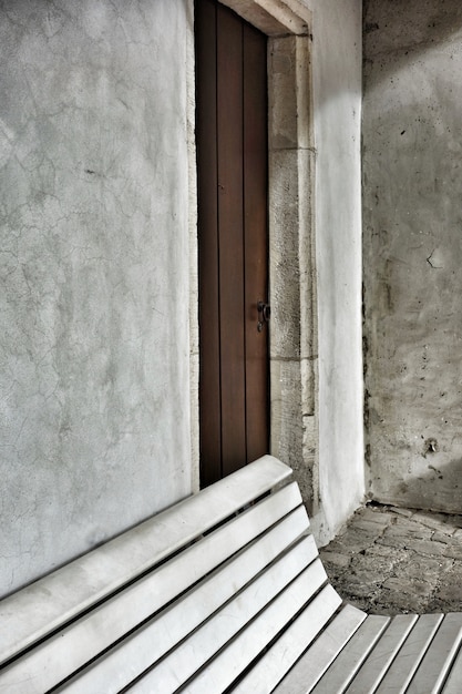 Foto gratuita colpo verticale di una panchina nel cortile accanto alla porta di una vecchia casa privata