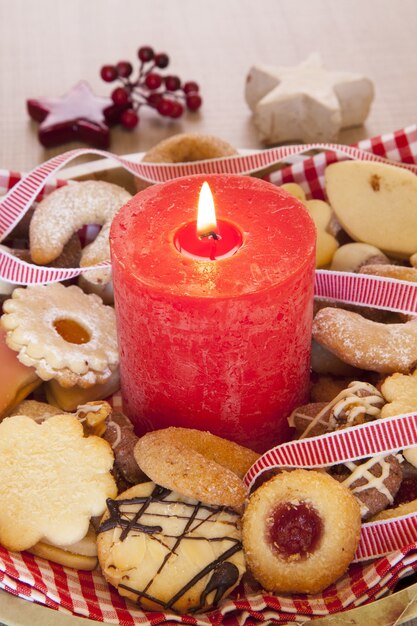 クリスマスのクッキーと装飾品と大きな赤い燃えるろうそくの垂直ショット
