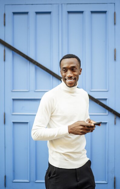 Vertical shot of a black man wearing a turtleneck holding his phone