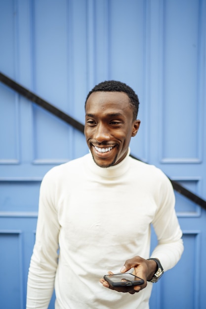 Vertical shot of a black man wearing a turtleneck holding his phone