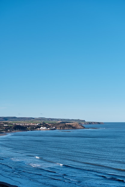 Foto gratuita colpo verticale di un mare blu e un cielo limpido durante il giorno