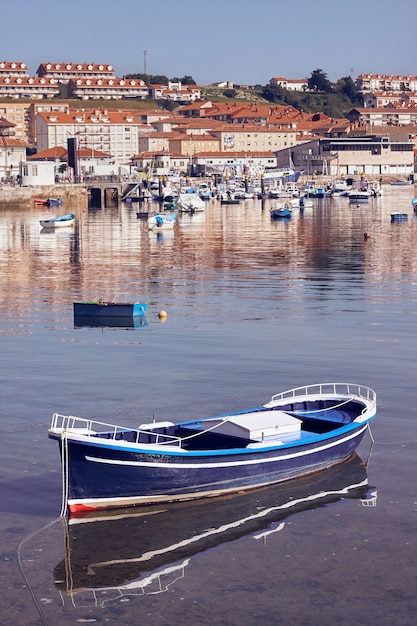 Vertical shot of a boat floating in water in front of a coast town