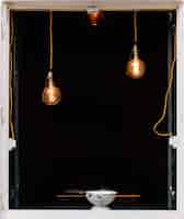 Free photo vertical shot of a bowl on a window with pendant lights and a black