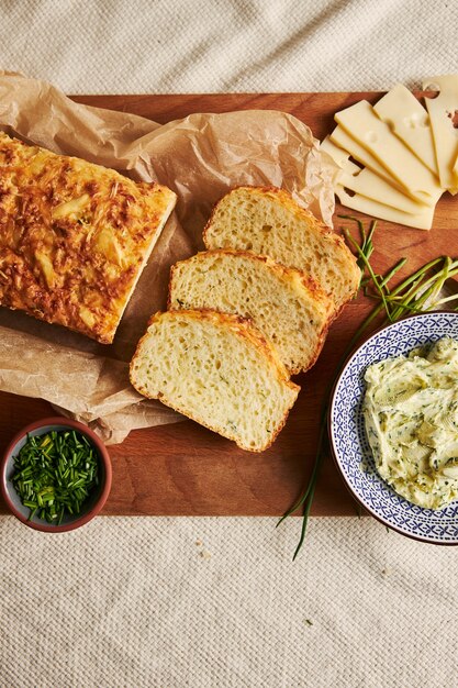 Вертикальный снимок хлеба с сырным травяным маслом на дереве