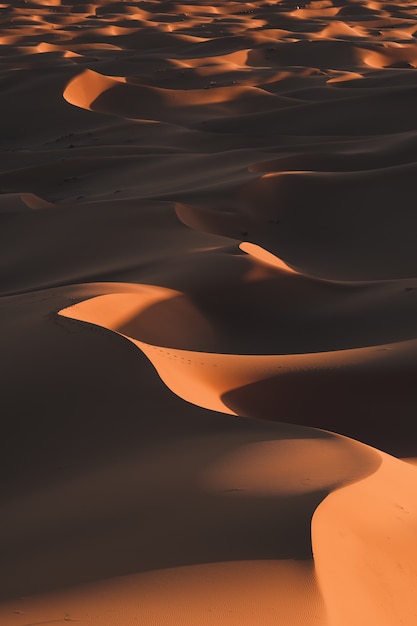 モロッコで撮影された日光の下で息をのむような砂漠の丘の垂直ショット