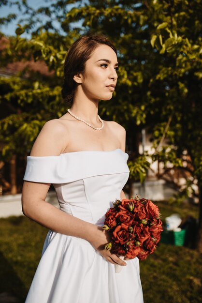 Vertical shot of a bride posing in a wedding dress outdoors