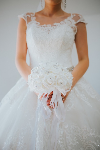 Free photo vertical shot of the bride wearing a beautiful white wedding gown on a gray