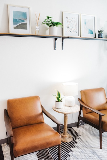 Free photo vertical shot of brown chairs with white lamp and a house plant in a table