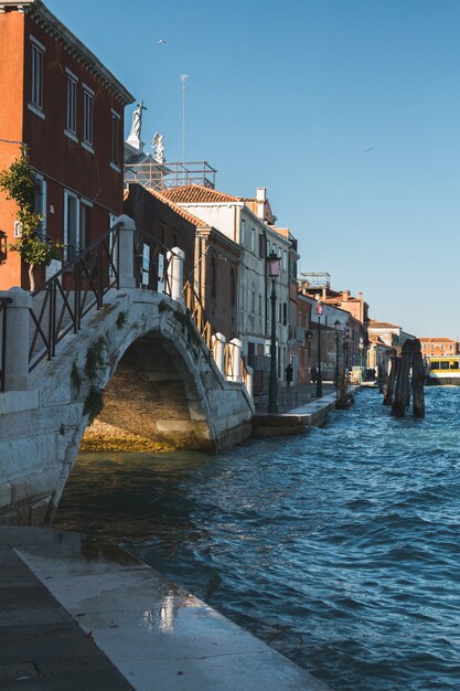 建物とイタリアのヴェネツィアの運河の水に架かる橋の垂直ショット