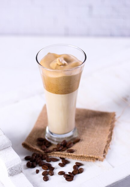 Vertical shot of a caramel smoothie on a brown napkin surrounded by coffee beans