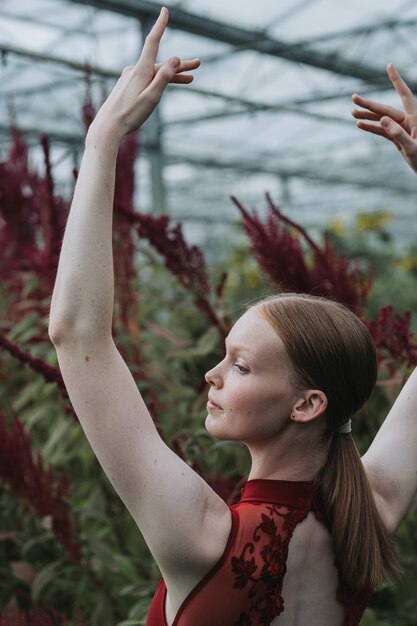 Vertical shot of a Caucasian female ballet dancer posing in burgundy costume