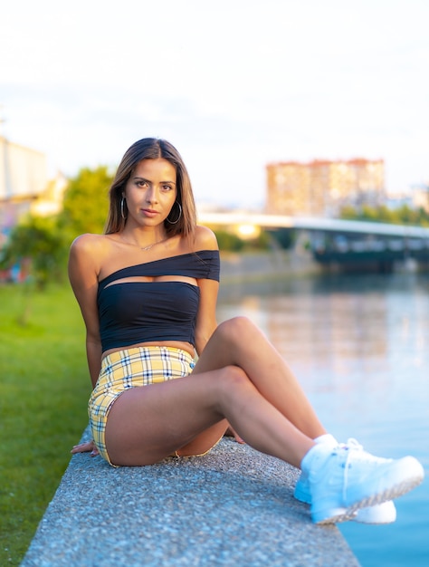 Vertical shot of a caucasian female wearing a yellow skirt while sitting in a park