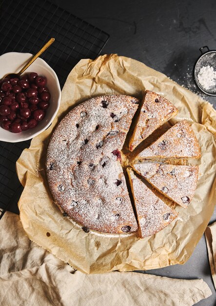 Vertical shot of a Cherry Cake with sugar powder and ingredients