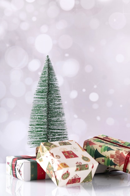 Vertical shot of Christmas gift boxes and small tree on bokeh