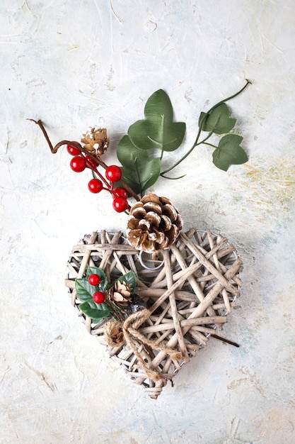 Foto gratuita colpo verticale di un cuore di legno decorativo a tema natalizio su una superficie di marmo bianco