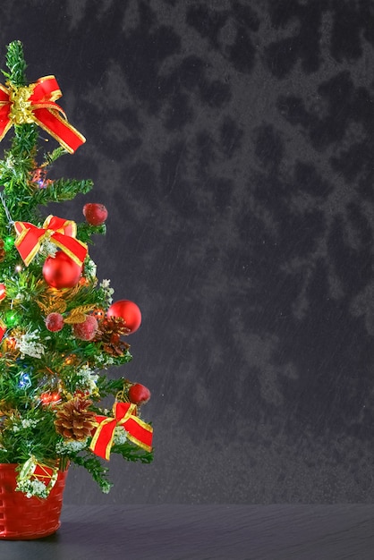 Vertical shot of a Christmas tree with red ornaments with a gray copy space background