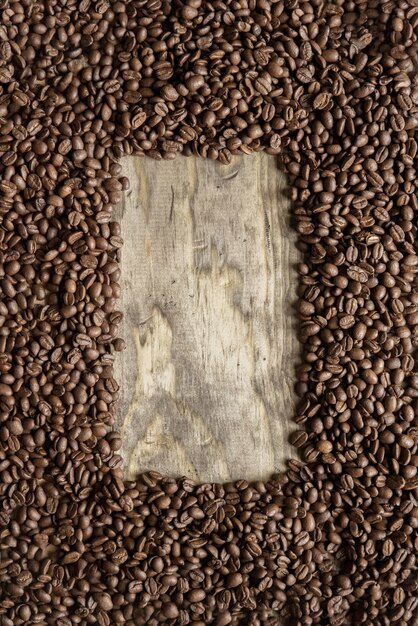 Vertical shot of a coffee beans frame over a wooden surface great for background or writing text