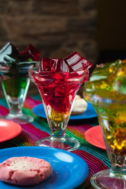 Вертикальный снимок красочных сладких желейных десертов рядом с тарелками для печенья