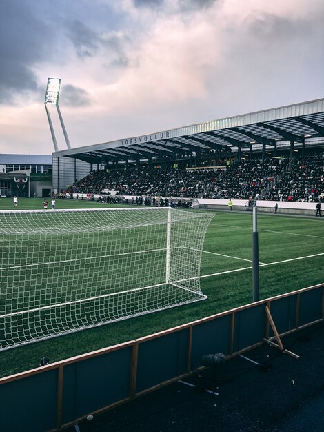 Vertical shot of crowded soccer stadium under cloudy sky