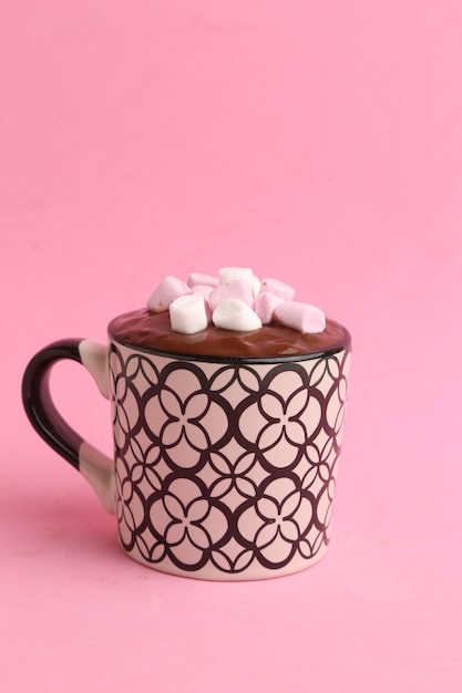 Вертикальный снимок чашки горячего шоколада с зефиром, изолированного на розовом фоне