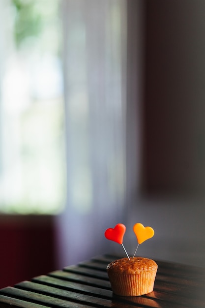 Free photo vertical shot of a cupcake with colorful hearts on it