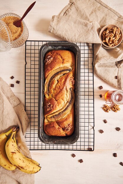 Vertical shot of delicious banana bread in a loaf pan with chocolate chunks and walnut on a table